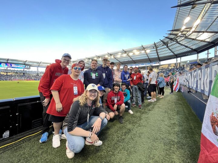 group of students stands in front of a soccor field