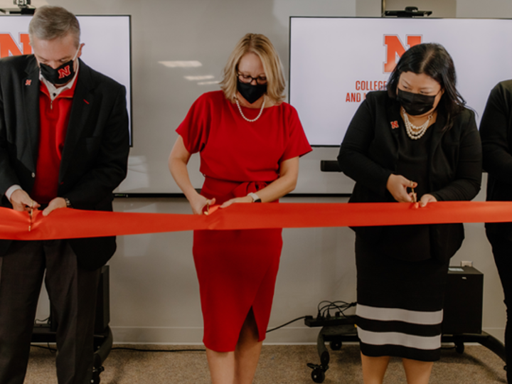 Four people stand ready to cut a red ribbon