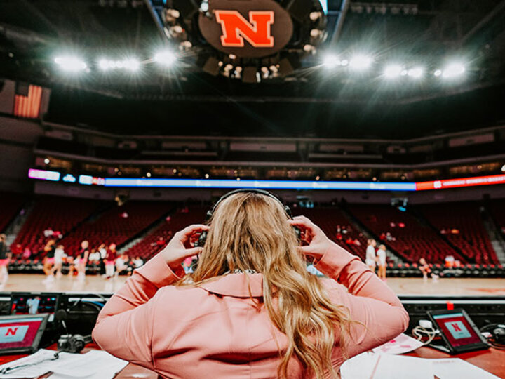 The back of a student putting on a headset to report on a basketball game.