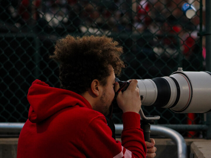 A College of Journalism student looks through the viewfinder of a camera.