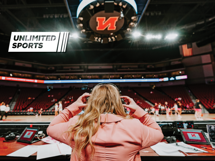 Woman puts on headphones in front of a basketball stadium