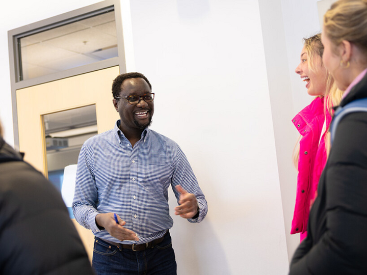 Dane Kiambi, associate professor of advertising and public relations, chats with students after a morning class in Andersen Hall.