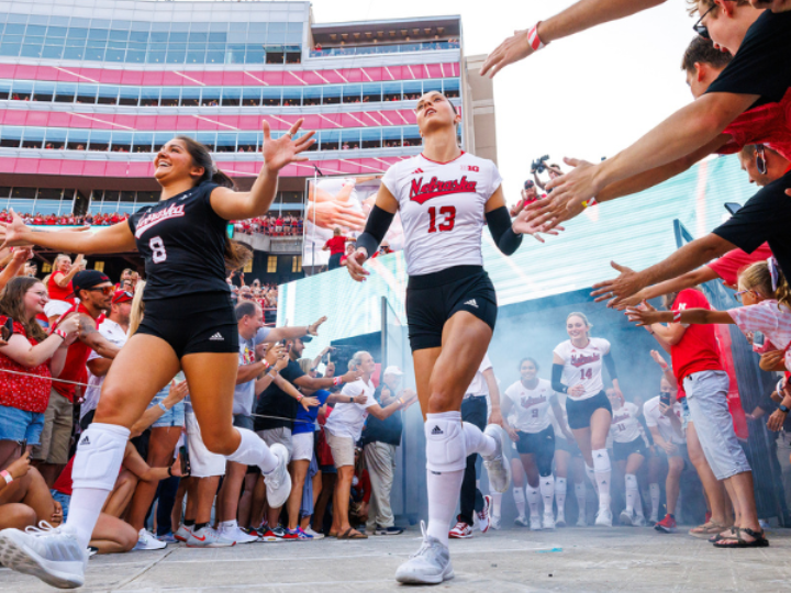 Lexi Rodriguez and her teammate running through the tunnle at memorial stadium on Volleyball Day 2023