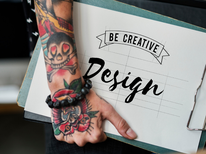 Tattooed arm holds clipboard that reads "Be Creative Design"