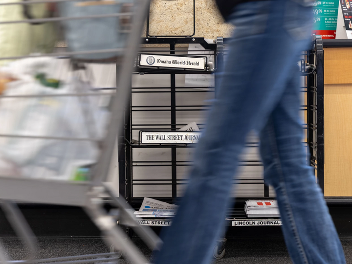 A grocery store shopper passes by a newsstand in Omaha where daily papers sit for sale on Oct. 8, 2025. The Omaha World-Herald and the Lincoln Journal-Star will no longer print a Monday edition starting in early November. (Naomi Delkamiller/The Midwest Newsroom)