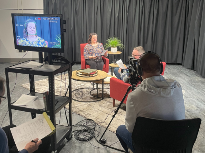 One person interviews another while a third films on a tv studio set