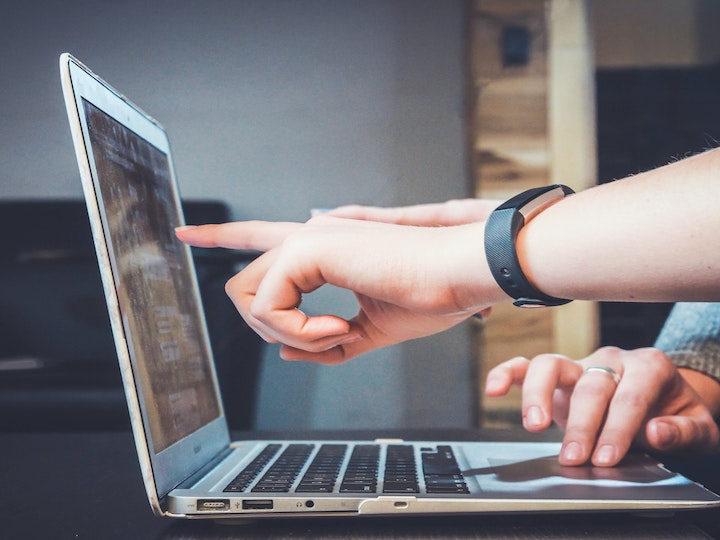 fingers pointing at laptop computer screen