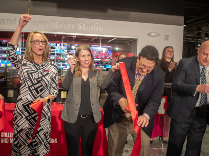 four people cutting a ribbon