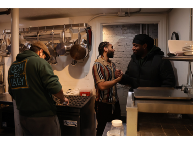 Every Face is a Friendly One A current program student, right, greets LaRue Marcos, middle, at 2:59 on Saturday, Feb. 21, 2026. Marcos now enters the Ooh De Lally kitchen as a director instead of a cook. However, the friendships he has built through graduating from the 180 Re-Entry Assistance Program are long-lasting. (Photo by/Hannah E. Herrera)
