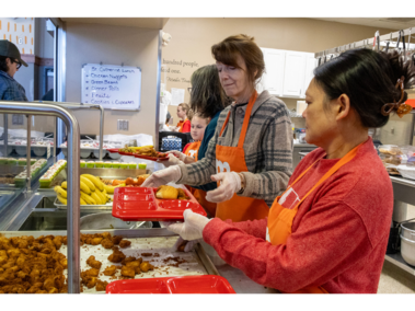 Linda Nelson, 63, and Mai Linebaugh, 54, both of Lincoln, Nebraska, prepare popcorn chicken and rolls on a tray for someone to sit down and eat at Matt Talbot Kitchen & Outreach on Saturday, Feb. 21, 2026, in Lincoln, Nebraska.