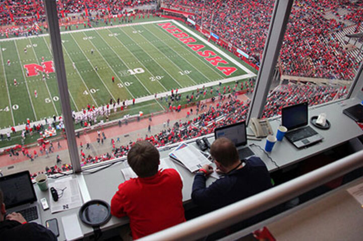 Students look out a large window over a football field