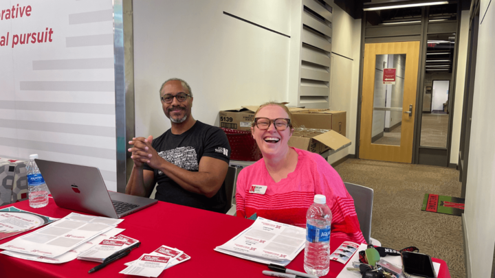 two people smiling in front of a check-in table