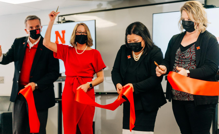 Four people cut a red ribbon