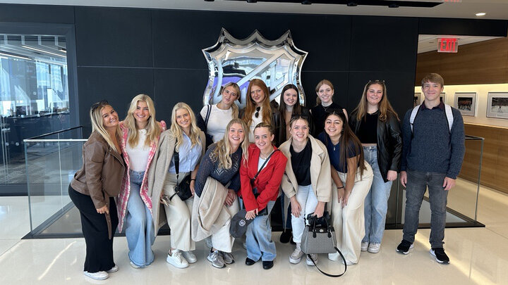 Group of Students pose in front of NHL logo