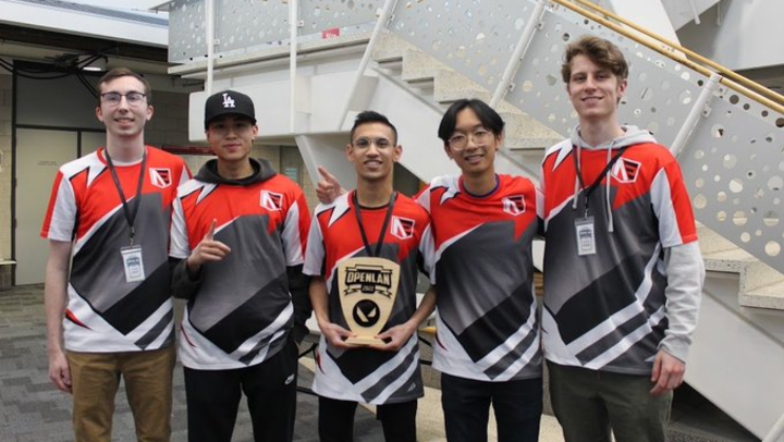 Five men poise with an esports trophy